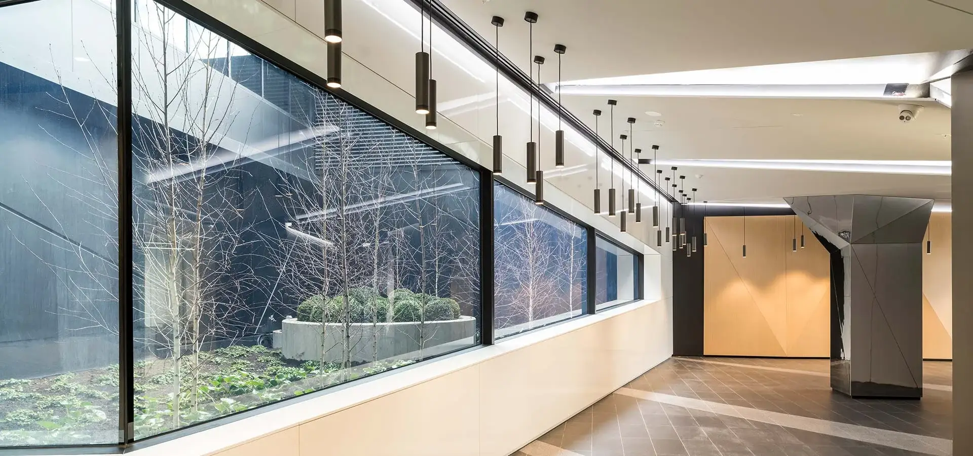 Interior courtyard with modern landscape design, architectural glass walls, feature lighting, and minimalist planting at 110 Church Street.