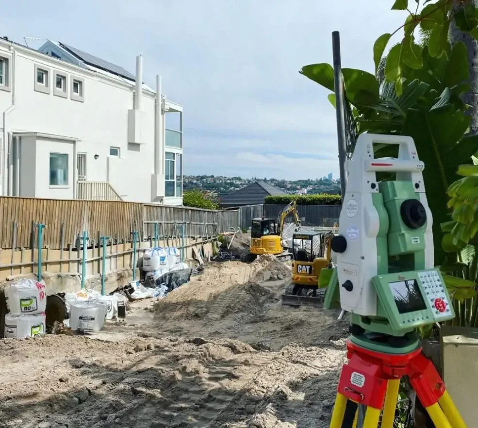 Construction site with survey equipment and earthworks in progress by Adaptive Green Space.