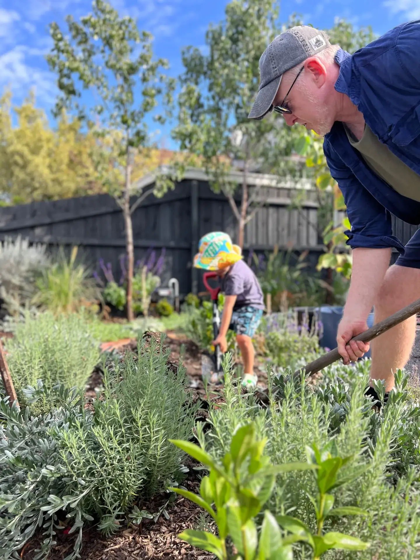 Man and child working together in a garden, planting and improving outdoor space.